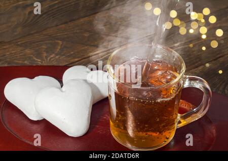 Tè caldo al vapore e pan di zenzero a forma di cuore. Messa a fuoco selettiva. Foto Stock