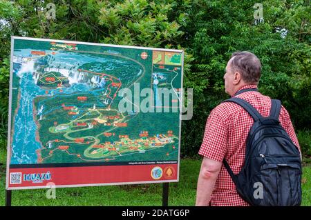 Un visitatore studia la grande mappa delle località delle cascate e dei sentieri per i piedi nel Parco Nazionale di Iguazu in Argentina. Le cascate di Iguazu sono la Foto Stock