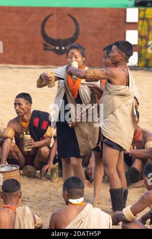 Naga uomini e donne che si siedono e si esibiscono in una tribale tradizionale Rituale nel villaggio di Kisama a Nagaland India durante la festa della hornbill Il 4 dicembre 2016 Foto Stock