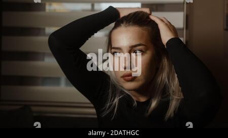 La giovane donna bionda annoiata si pone guardando la macchina fotografica, lo stile di vita e il concetto pandemico Foto Stock