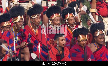 I tribisti di Naga indossano il loro abbigliamento tradizionale e si siedono insieme Kisama Village Arena a Nagaland India il 4 dicembre 2016 Foto Stock