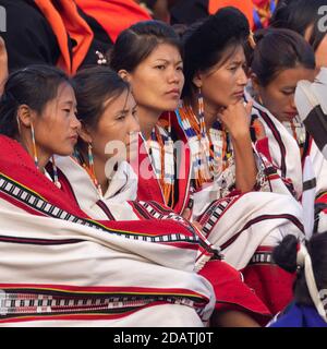 Giovani tribeswomen Naga che si siedono insieme indossando abbigliamento colorato e scialli Kisama Heritage Village a Nagaland India il 3 dicembre 2016 Foto Stock