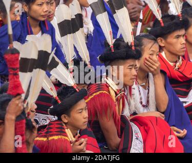 I ragazzi e le ragazze di Naga giovani si siedono insieme indossando l'abito colorato E scialle in Kisama Heritage Village a Nagaland India ON 3 dicembre 2016 Foto Stock