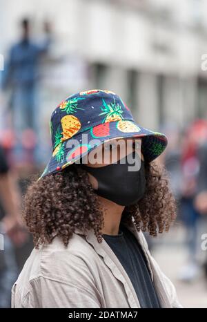 Una donna indossa una maschera facciale e un colorato cappello da sole durante una protesta Black Lives Matter. Foto Stock