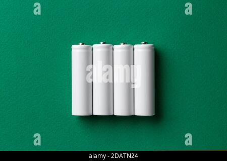 Batterie ricaricabili AAA bianche su sfondo verde. Posiziona per il testo. Concetto di energia verde. Foto Stock