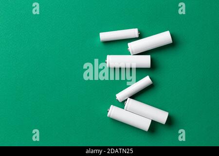 Batterie ricaricabili AAA bianche su sfondo verde. Posiziona per il testo. Concetto di energia verde. Foto Stock