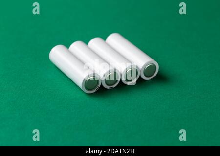 Batterie ricaricabili AAA bianche su sfondo verde. Posiziona per il testo. Concetto di energia verde. Foto Stock
