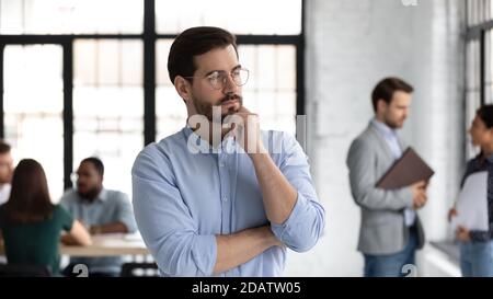 Un giovane leader ponderato che sta riflettendo nell'area di lavoro dell'ufficio Foto Stock