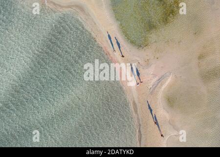 Vista aerea delle persone che camminano e gettano lunghe ombre sul sandbar della spiaggia di Elafonisi, una delle destinazioni turistiche più popolari nel sud Foto Stock
