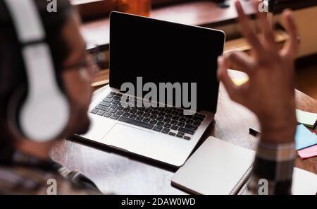 Guy at laptop gesturing OK a vuoto schermo del computer indoor Foto Stock