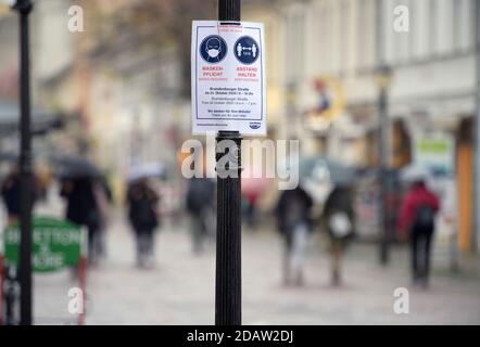 Potsdam, Germania. 30 Ott 2020. Un poster con la scritta "Mask obbligation" e "Keep Distance" è appeso su un lampione a Brandenburger Straße. Secondo il nuovo regolamento per affrontare la pandemia della corona, le coperture della bocca e del naso devono essere indossate in luoghi più frequentati della città. Credit: Soeren Stache/dpa-Zentralbild/ZB/dpa/Alamy Live News Foto Stock