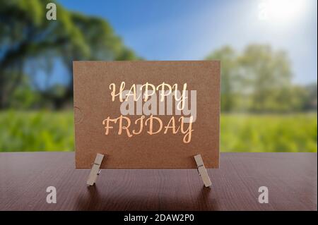 Carta Happy Friday sul tavolo con sfondo verde soleggiato foresta. Foto Stock