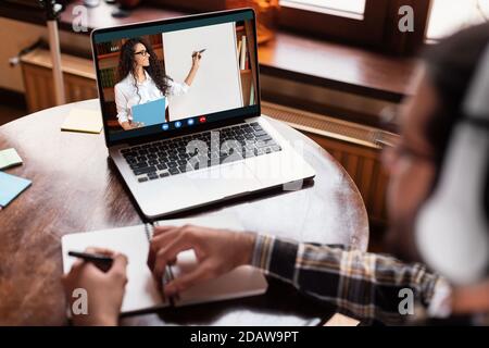 Studente Guy al portatile con classe online seduto a casa Foto Stock