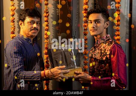 Ritratto di due uomini indiani che scambiano doni in occasione delle feste di Diwali. Celebrazioni a casa. Foto Stock