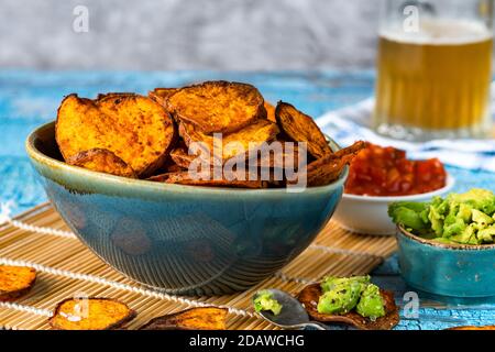 Patatine dolci speziate fatte in casa con avocado e pomodoro schiacciati salsa Foto Stock