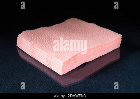 I tovaglioli di carta rosa su sfondo nero. Asciugamano Hygenic su tavola di vetro con riflesso Foto Stock