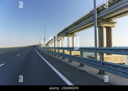 Nuova strada asfaltata sul ponte stradale sullo stretto di Kerch. La linea ferroviaria corre in alto sulla destra Foto Stock