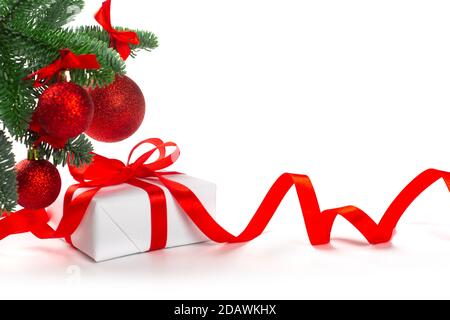 Scatola regalo regalo bianca per le feste con arco in raso rosso e nastro ricci sotto l'albero di Natale con baubles, cornice di bordo isolata su sfondo bianco Foto Stock