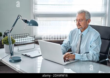 Ritratto di un uomo anziano. Un uomo anziano che lavora su un computer portatile. Lavori di rimozione, freelance. Foto Stock