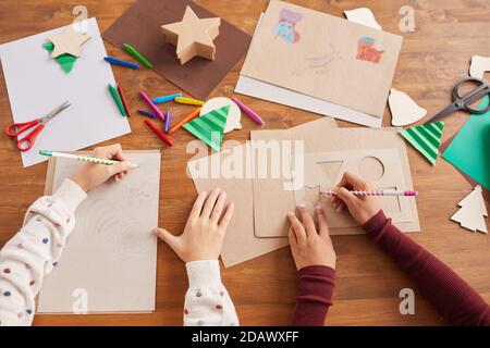 Vista dall'alto primo piano dei bambini che disegnano immagini durante la lezione d'arte e di artigianato a scuola, copy space Foto Stock