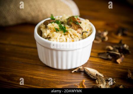 riso cotto con funghi secchi su un tavolo di legno Foto Stock