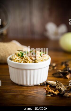 riso cotto con funghi secchi su un tavolo di legno Foto Stock