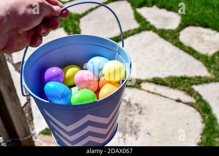 Uomo che tiene il secchio colorato delle uova di Pasqua per la Domenica di Pasqua Caccia all'uovo di Pasqua Foto Stock