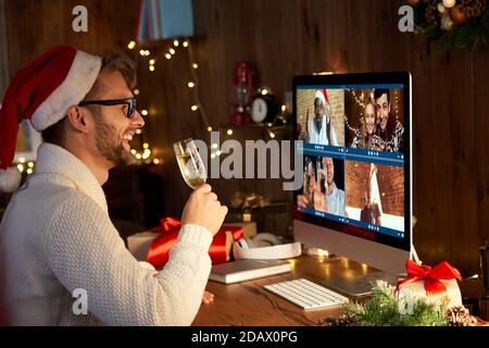 Happy man indossa il cappello di santa per festeggiare il nuovo anno con gli amici in videochiamata. Foto Stock