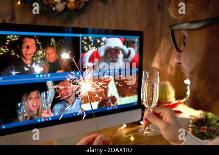 Il giovane indossa il cappello di Natale festeggia l'felice anno nuovo con una videochiamata. Foto Stock
