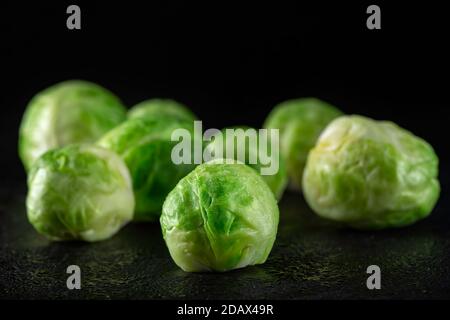 germogli di bruxelles freschi su ardesia scura pronti per essere cotti Foto Stock