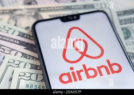 Stafford / Regno Unito - Novembre 15 2020: Il logo dell'app Airbnb visto sullo schermo dello smartphone, messo sulle bollette del dollaro. Foto Stock