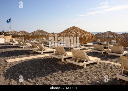 Santorini, Grecia - 16 settembre 2020: Ombrelloni di paglia con lettini presso la spiaggia di Vlychada, sul lato meridionale di Santorini, Cicladi, Greecee Foto Stock