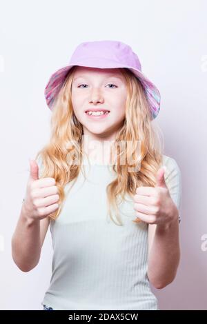 Pre-teen, ragazza dai capelli giusti con gli occhi blu che portano un cappello del secchio. Foto Stock