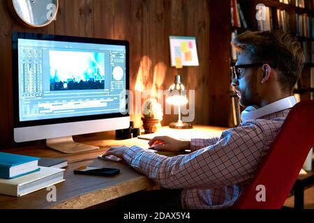 Videografo maschile che utilizza il computer editing video filmati video contenuti visivi. Foto Stock