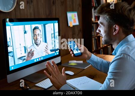 Consulente finanziario caucasico che consulta il cliente africano su videoconferenza chiamata. Foto Stock