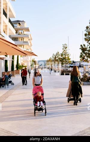 Madre sta spingendo il suo bambino in un passeggino rosa mentre A piedi su un molo per barche a Porto Montenegro Foto Stock