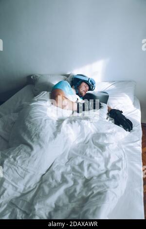 Uomo nel letto con lo snowboard ski googles e casco Foto Stock