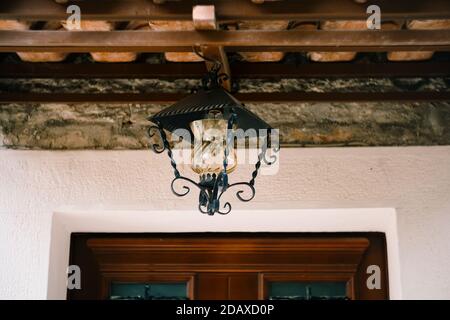 Lampada da strada appesa alla porta di legno anteriore con elementi in metallo forgiato. Foto Stock
