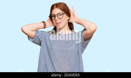 Giovane donna di testa di lettura che indossa abiti e occhiali casual cercando di sentire entrambe le mani sul gesto dell'orecchio, curiosa per pettegolezzi. Problema di udito, sordi Foto Stock