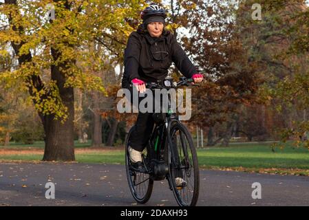 11/14/2020. Parco Stromovka. Praga. Repubblica Ceca. Una donna sta cavalcando la sua bicicletta al parco in una giornata invernale. Foto Stock