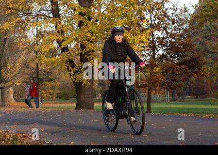 11/14/2020. Parco Stromovka. Praga. Repubblica Ceca. Una donna sta cavalcando la sua bicicletta al parco in una giornata invernale. Foto Stock