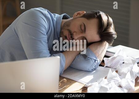 Il dipendente dell'ufficio che dormiva seduto alla scrivania si mette la testa sulle braccia Foto Stock
