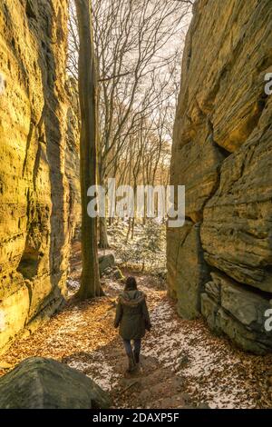 Donna singola che cammina attraverso la fessura di roccia in un paesaggio d'inverno dorato Foto Stock