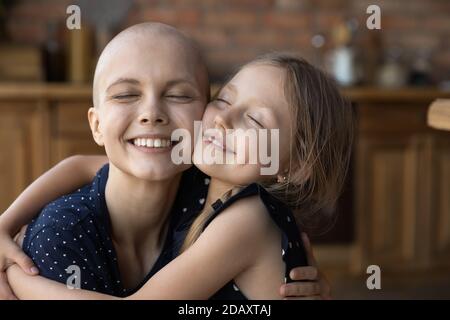 Affettuosa figlia piccola coccolando amata mummia malata che soffre di cancro Foto Stock