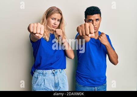 Giovane coppia interracial che indossa abiti casual pugno pugno per combattere, aggressivo e arrabbiato attacco, minaccia e violenza Foto Stock