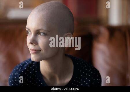 Paziente oncologico femminile pensieroso seduto sul divano guardando da parte meditare Foto Stock