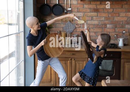 Madre e figlia malate eccitate che lottano per il divertimento in cucina Foto Stock