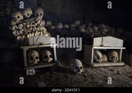 Teschi umani scatolati al Cimitero di Fontanelle (Cimitero delle Fontanelle) a Napoli, Campania, Italia. L'ex caserma (ossario) situata in una grotta del distretto di Materdei era il luogo in cui si sviluppò a Napoli il culto spontaneo della devozione ai resti di morti senza nome. I difensori del culto hanno pagato visite ai teschi senza nome nell'ossario per adottarli e persino dare i nomi dei teschi. I teschi adottati furono collocati all'interno della scatola decorata e diventarono oggetto di regolare offerta orante e votiva. Foto Stock