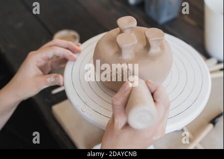 Le mani della donna del vasaio stanno modellando una tazza da una creta. Il processo di creazione della ceramica. Il maestro ceramista lavora nel suo studio. Primo piano, solo le mani Foto Stock