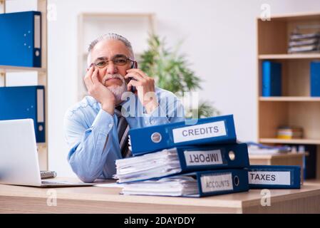 Anziano contabile di sesso maschile infelice con lavoro eccessivo sul posto di lavoro Foto Stock